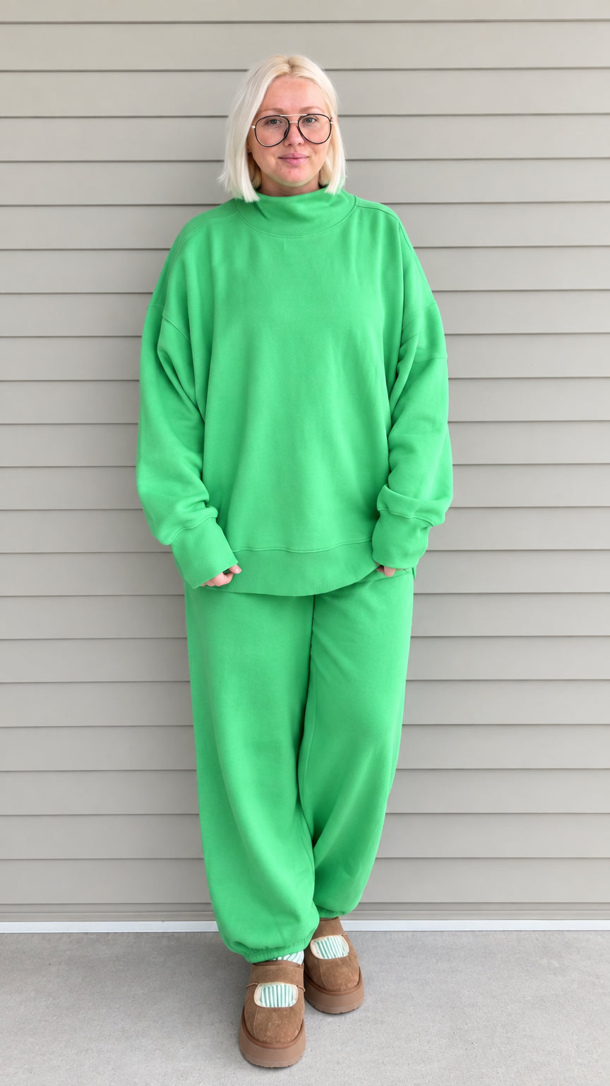 Front full view of woman wearing green oversized mock neck sweatshirt and matching jogger pants set