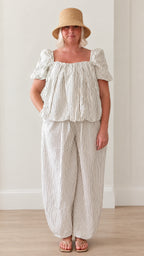 Front view of woman wearing white striped square neck puff sleeve top and lantern pants set