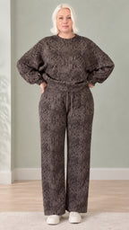 Front full view of woman wearing dark brown snakeskin print sweatshirt and wide-leg pants lounge set