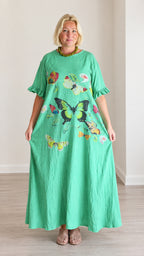 Front view of woman wearing a loose green butterfly print maxi dress with ruffle sleeves