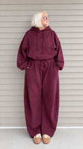 Front full-length view of woman wearing burgundy oversized hoodie and wide-leg sweatpants lounge set