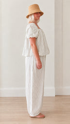 Side profile of woman wearing white striped coordinated top and balloon pants set