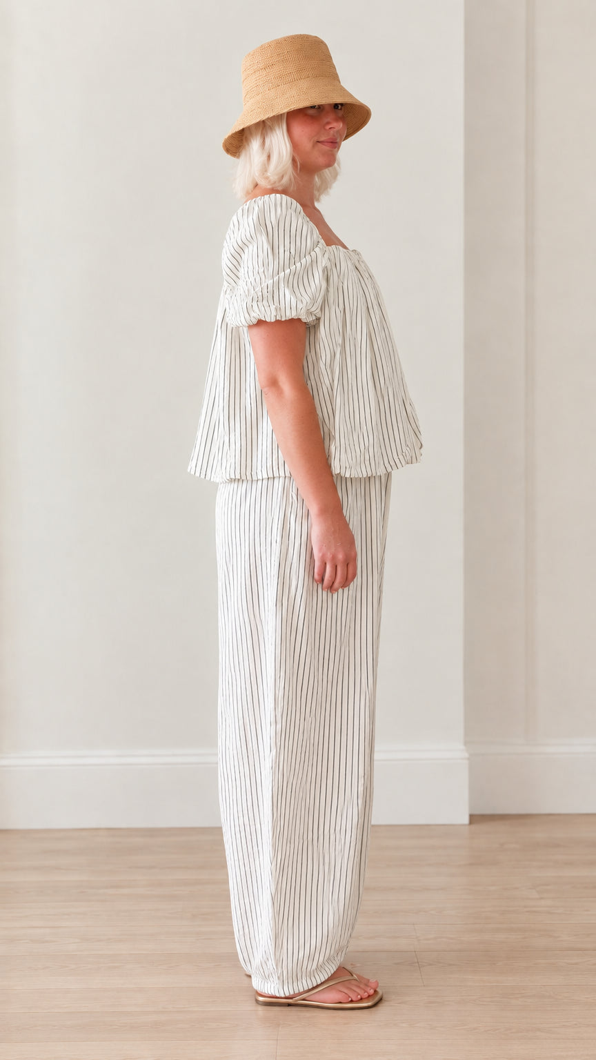 Side profile of woman wearing white striped coordinated top and balloon pants set