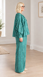 Side profile view of model in green striped balloon-sleeve top and matching wide-leg trousers