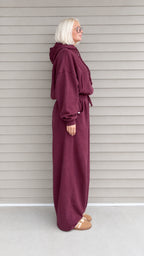 Side profile view of woman wearing burgundy 2-piece hoodie and sweatpants set