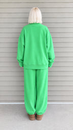 Back view of woman wearing green mock neck sweatshirt and loose cuffed sweatpants