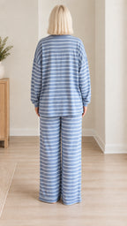 Back view of woman wearing blue striped pajama set with wide leg trousers