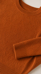 Close-up detail of textured knit fabric, ribbed neckline, and sleeve cuff in rust orange