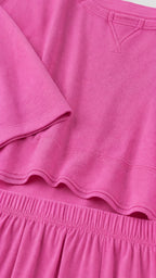 Close-up detail of fuchsia knit fabric neckline and elastic waistband