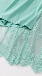 Close-up detail of mint green knit fabric hem and delicate floral eyelash lace