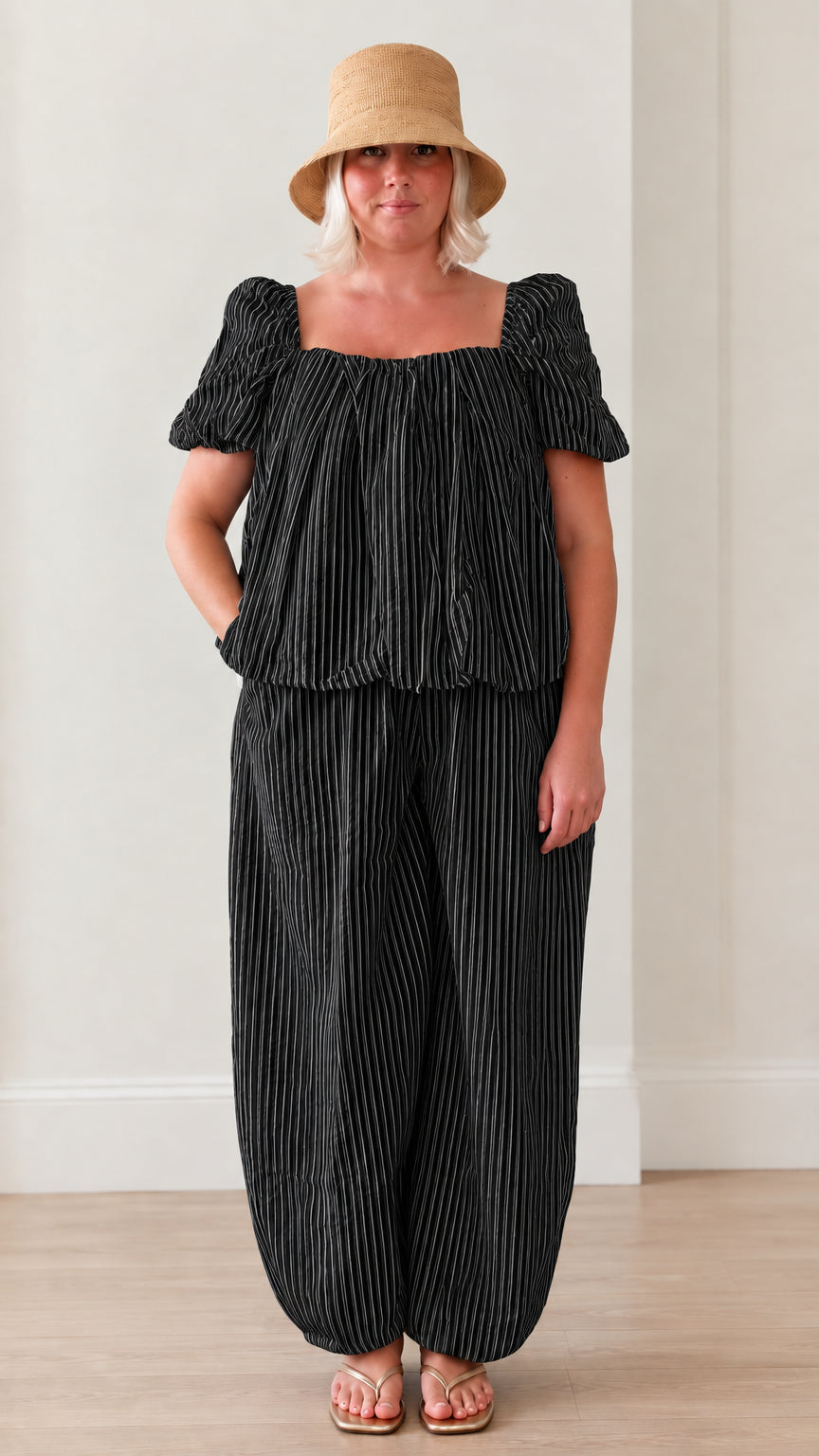 Woman wearing black striped square neck puff sleeve top and matching lantern pants set