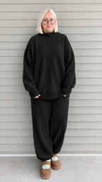 Full front view of woman wearing black oversized mock neck sweatshirt and jogger pants set