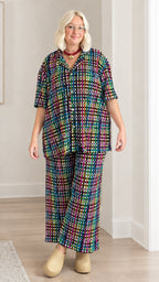 Model wearing dark multicolor plaid short sleeve shirt and matching wide-leg pants set