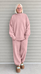Full front view of woman wearing dusty pink oversized mock neck sweatshirt and jogger pants set