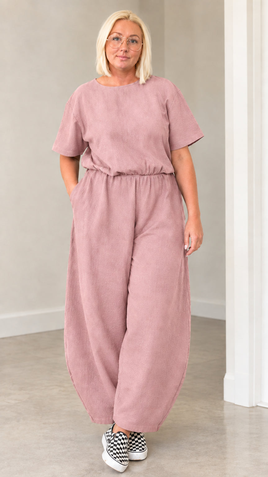 Front view of woman wearing dusty pink short sleeve lantern jumpsuit