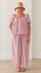 Woman wearing pink striped square neck puff sleeve top and matching lantern pants set