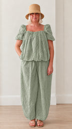 Woman wearing sage green striped square neck puff sleeve top and matching lantern pants set