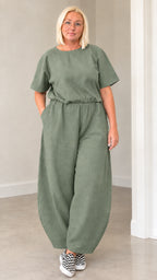Front view of woman wearing sage green casual lantern jumpsuit