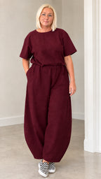 Front view of woman wearing burgundy wine red lantern jumpsuit