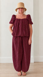 Woman wearing burgundy striped square neck puff sleeve top and matching lantern pants set