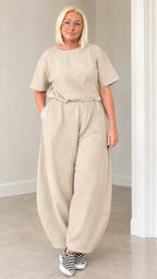 Front view of woman wearing beige oatmeal short sleeve lantern jumpsuit